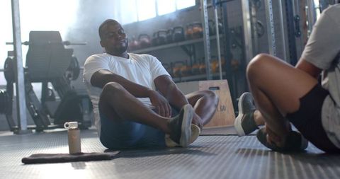 African American men stretching together in gym doing partner core warm-up before training
