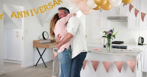 Happy couple celebrating anniversary at home embracing