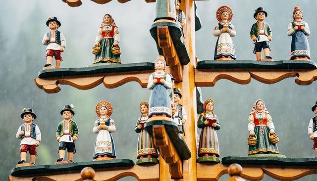 Displaying handpainted wooden folk figurines on tiered market shelf in rain