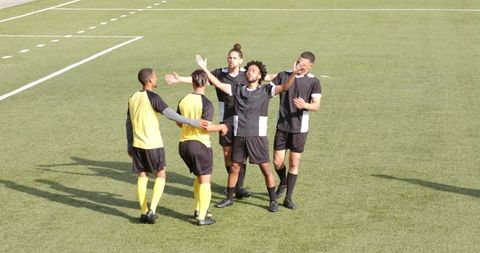 Soccer Team Celebrating Goal on Grass Field in Sunny Day