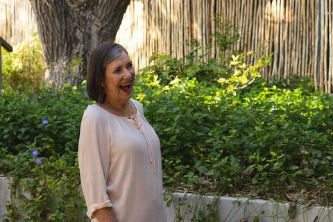 Senior woman laughing by garden with purple flowers