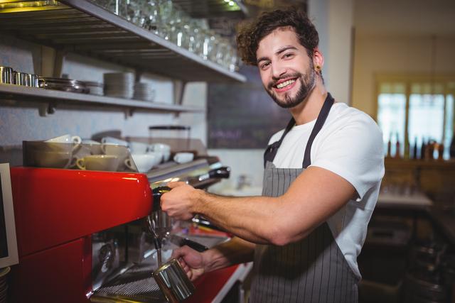 Portrait of smiling waiter making cup of coffee in cafe