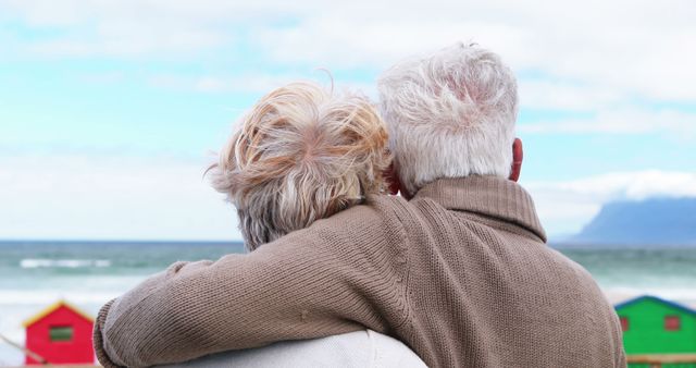 Elderly Couple Embracing by the Beach with Colorful Huts - Download Free Stock Images Pikwizard.com