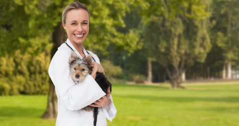 Smiling Female Vet Holding Yorkie Terrier in Park Environment