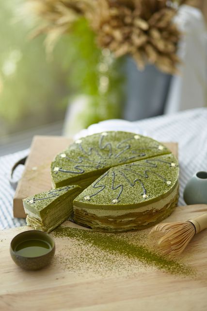 Sophisticated matcha mille crepe cake with a slice cut out, showcasing layers of delicate green tea-flavored crepes. Perfect for blogs, food photography, culinary magazines, dessert recipes, and healthy eating promotions.