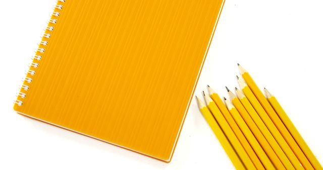 Ideal for education and back-to-school promotions, this image showcases yellow notebook with several sharpened pencils on a white background. Useful in articles or advertisements about school supplies, office materials, and study tips.