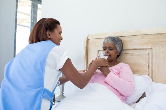 Nurse Assisting Elderly Woman in Bed with Glass of Water - Download Free Stock Photos Pikwizard.com