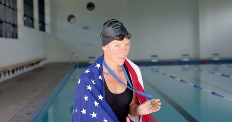 Proud female swimmer champion displaying medal by swimming pool
