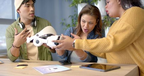 Diverse team examining futuristic vr headset prototype during collaborative design meeting
