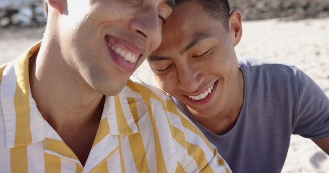 Happy diverse gay male couple embracing by the sea. Summer, vacations, relationship, romance and free time, unaltered.