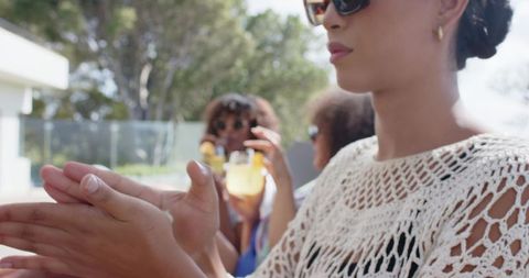 African american women enjoying poolside brunch clapping and sipping citrus cocktails