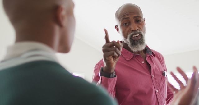 Image of nervous african american father arguing with son in kitchen. Parenthood, family, emotions and upbringing concept.