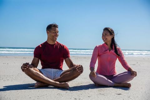 Diverse Couple Practicing Yoga on Beach Promoting Mindfulness