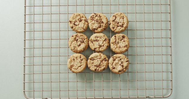 Nine freshly baked chocolate chip cookies arranged in a 3x3 grid on a cooling rack. Ideal for use in food blogs, cooking websites, bakery promotions, or recipe illustrations.