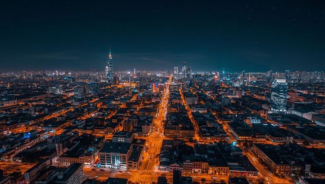 Illuminated central avenue stretching through urban nightscape with neon traffic trails