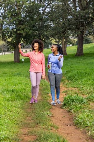 African american friends walking and taking selfie on park trail during fitness walk