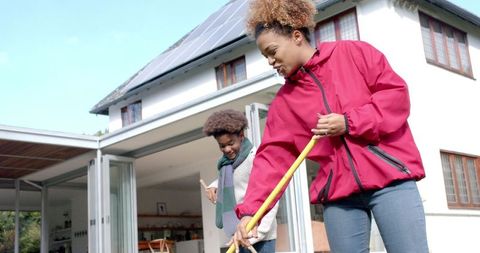 Mother and son raking leaves together in garden