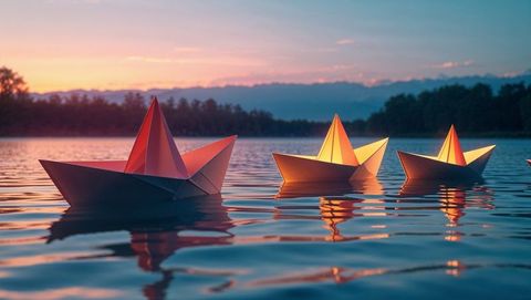 Serene origami paper boats on lake at sunset