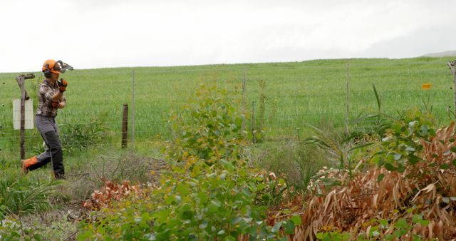 Worker with Chainsaw in Green Field Wearing Protective Gear - Download Free Stock Images Pikwizard.com