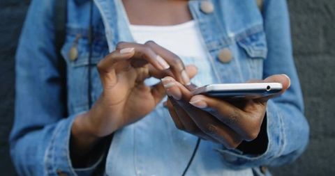 Woman Engaging with Smartphone Against Urban Wall