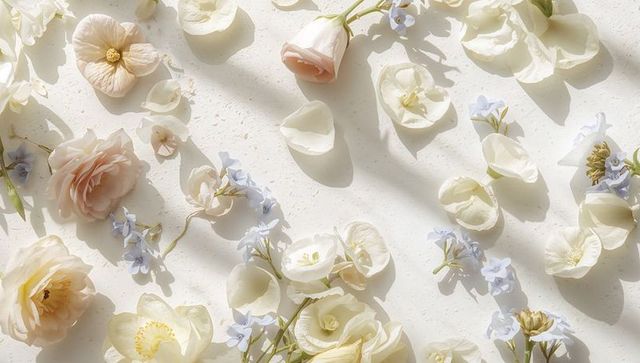 Pastel floral flat lay featuring cream roses, blush ranunculus and pale blue filler