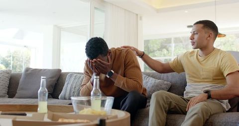 Multiracial friends consoling on sofa offering emotional support for men's mental health