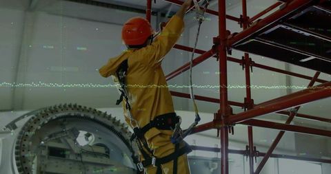 Industrial technician securing on red scaffold with safety gear
