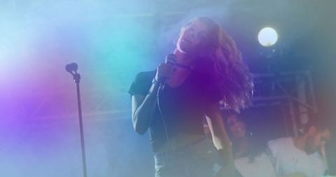 Energetic female singer performing on vibrant concert stage