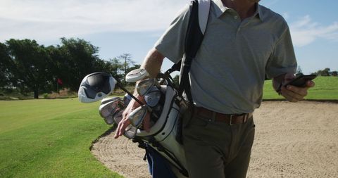 Golf Player Holding Clubs While Using Smartphone on Sandy Course - Download Free Stock Images Pikwizard.com