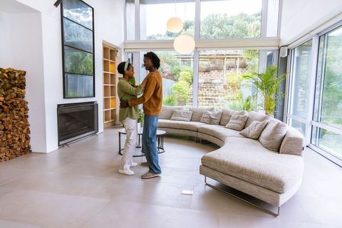 African american couple embracing in modern living room with curved sofa and fireplace