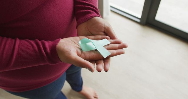 Close-up of Hands Holding Teal Ribbon for Awareness Support Indoors - Download Free Stock Images Pikwizard.com