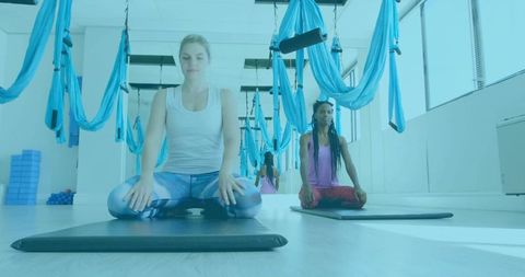 Women Meditating in Yoga Studio with Aerial Hammocks