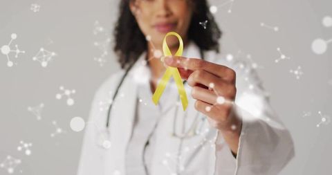Doctor holding yellow awareness ribbon with science background