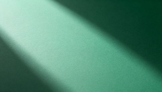 Textured green surface showing diagonal light and shadow minimal abstract composition