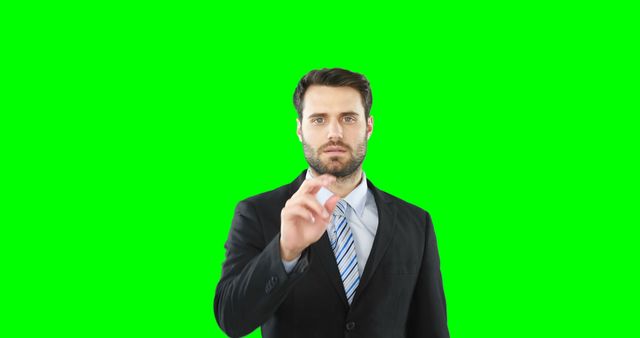Businessman wearing suit and tie interacts with a virtual screen. Green background can be replaced with customizable visuals, making this image useful for presentations, advertisements, tech tutorials or digital business concepts.