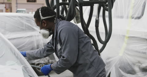 Mechanic Using Grinder on Car in Workshop