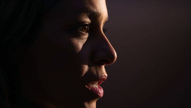Woman in dramatic low-key profile portrait capturing warm directional light on face