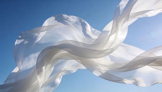 Billowing sheer silk ribbons flowing across clear blue sky with sunlit translucent veils