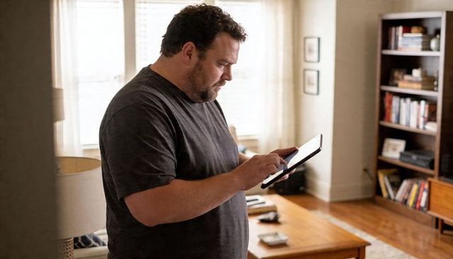 Overweight Man Using Tablet in Cozy Living Room During Daylight Home Technology Moment