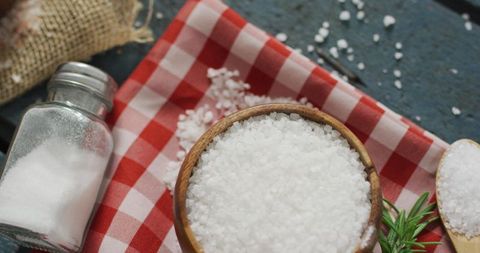 Coarse sea salt in wooden bowl on checkered cloth
