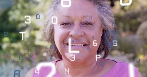 Smiling senior woman wearing pink top in sunlit garden with floating alphanumeric overlay