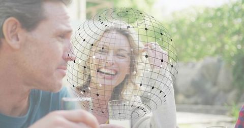 Laughing couple enjoying sunlit backyard brunch with floating wireframe globe overlay