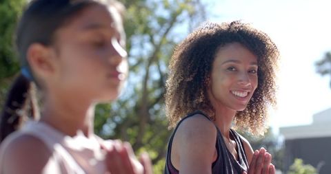 Mother and Daughter Practicing Yoga Outdoors in Sunny Garden