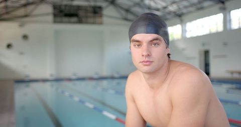 Male Swimmer in Swim Cap by Pool Reflecting Athlete's Focus