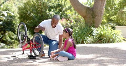 Father Teaching Daughter to Fix Bicycle in Park