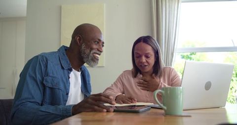 Senior couple reviewing finances and planning budget with laptop and tablet