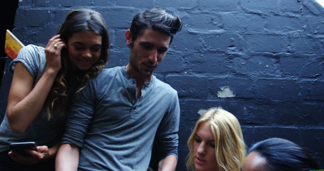 Group of friends socializing and chatting outdoors in a casual setting. They are wearing casual clothing and appear to be enjoying each other's company. This image could be used for representing friendship, social interactions, youth culture, and leisurely activities.