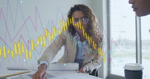Female executive analyzing blueprints with financial charts overlay in modern office team