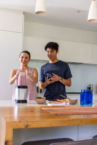 Couple preparing smoothie and chopping fruit on modern bright kitchen island