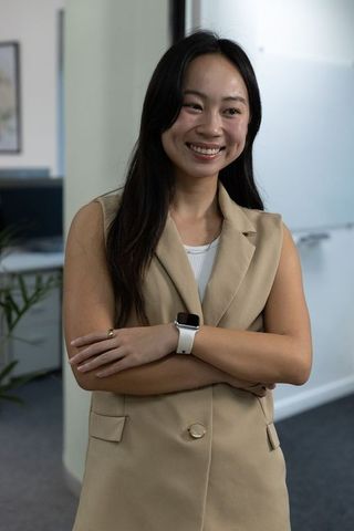 Confident chinese businesswoman wearing smartwatch smiling with arms crossed in office